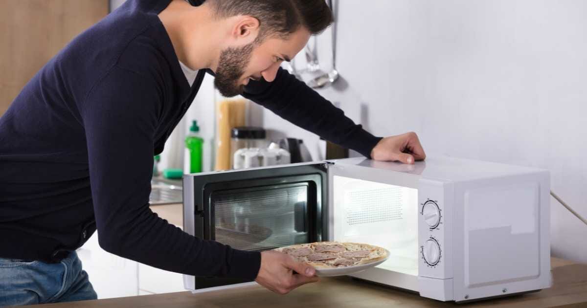 man heating up pizza